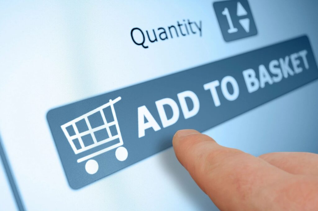 Finger pressing 'Add to Basket' button on an online shopping site.